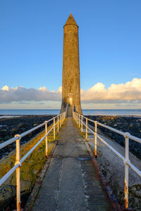 Walkway by sea against sky