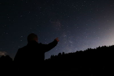 Low angle view of silhouette man gesturing at star field