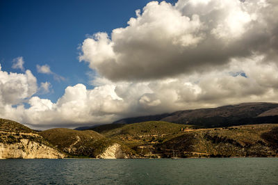 Scenic view of sea by mountains against sky