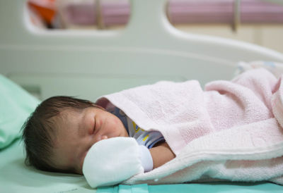 Close-up of cute newborn sleeping on bed at hospital