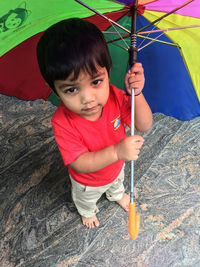 Portrait of cute boy holding umbrella while standing outdoors