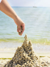 Cropped hand making sandcastle at beach