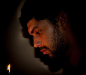 Close-up of young man by flame in darkroom