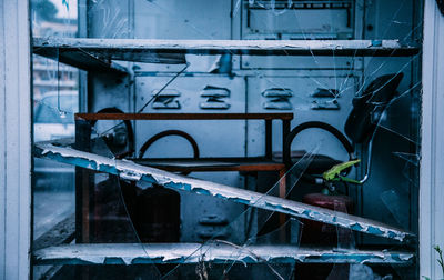 Machinery and fire extinguisher in abandoned factory seen through broken glass
