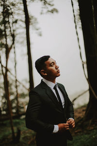 Portrait of businessman standing against trees