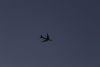 Low angle view of silhouette airplane against clear sky