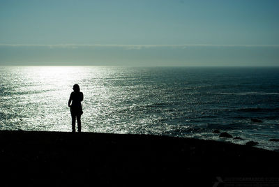 Silhouette man standing on beach against sky