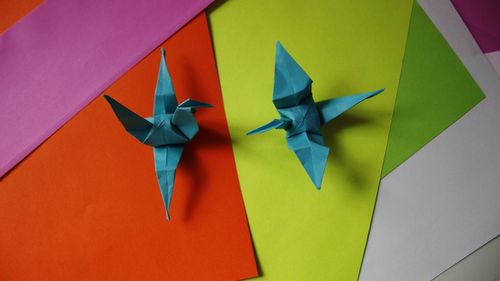 High angle view of origami over multi colored paper on table