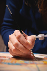 Hand of artist with brush painting on canvas, close-up .