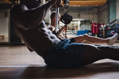 Sports people doing strength training while exercising with barbell in gym