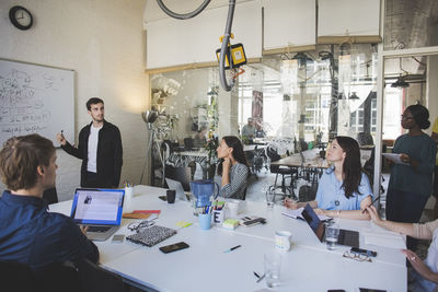 Creative businessman brainstorming colleagues during meeting in board room