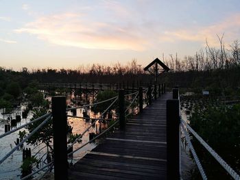 Footbridge over jetty against sky during sunset