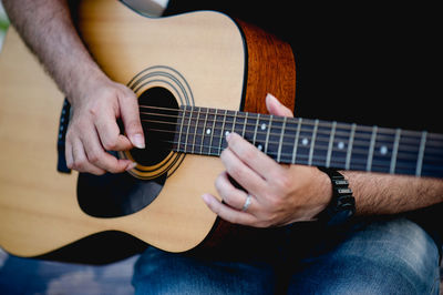 Midsection of man playing guitar outdoors