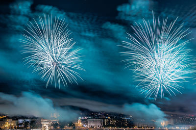 Low angle view of firework display over illuminated city at night