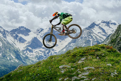 Rear view of man riding bicycle on mountain against sky