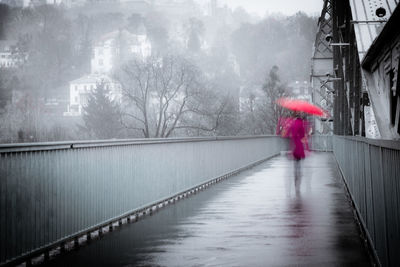 Rear view of woman walking on wet road during winter