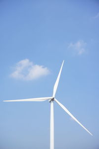 Low angle view of wind turbine against blue sky