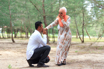 Man kissing girlfriend on hand against trees