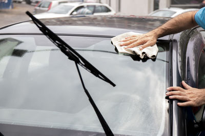 Satisfied mature man polishing his car with microfiber cloth. close-up