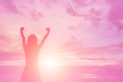 Silhouette hand against pink sky during sunset