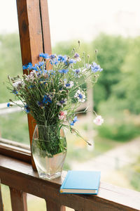 A bouquet of cornflowers and a book on the windowsill in a cozy home.