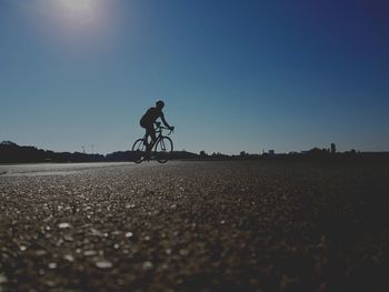 Man riding bicycle on road against clear sky