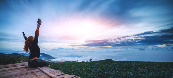 Rear view of woman standing by sea against sky