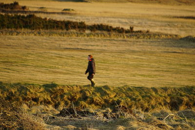 Side view of boy walking on field