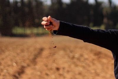 Midsection of person releasing mud over field