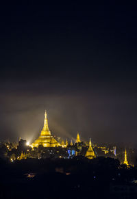 Illuminated buildings in city against sky at night