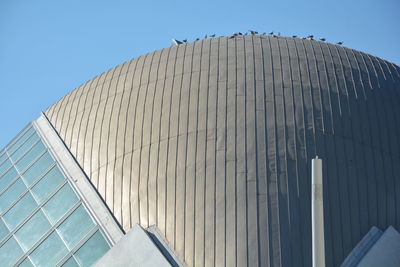 Low angle view of modern building against sky with birds