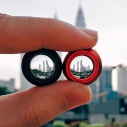 Cropped hand holding lens in front of petronas towers