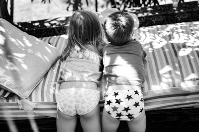 Rear view of siblings lying on bed