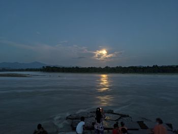 People on beach against sky during sunset