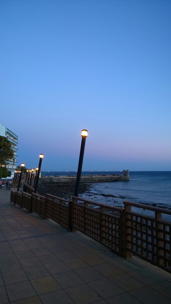 clear sky, sea, water, horizon over water, copy space, blue, pier, railing, tranquility, tranquil scene, nature, scenics, built structure, jetty, beauty in nature, wood - material, sky, outdoors, beach, street light