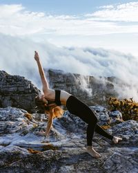 Woman with arms raised against sky