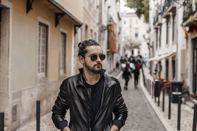 Portrait of young man standing on street in city