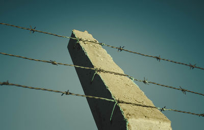 Low angle view of barbed wire against clear sky