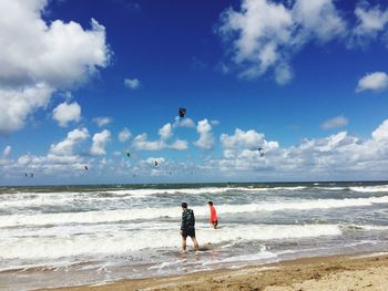 Men standing in sea against blue sky during sunny day