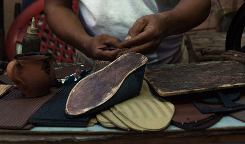 Midsection of man working on shoe in workshop