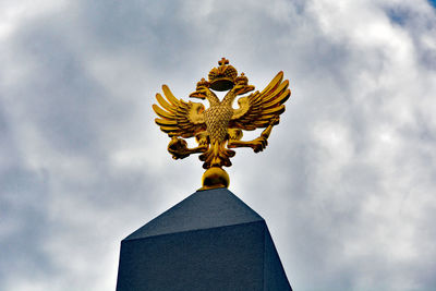 Low angle view of angel statue against cloudy sky