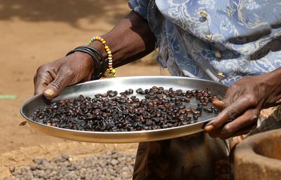 Midsection of woman holding plate with coffee beans