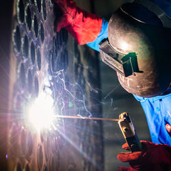 Close-up of man welding metal at night