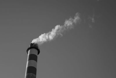 Low angle view of smoke emitting from chimney against sky