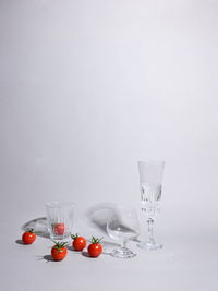 Fruits in glass on table against white background