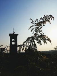 Low angle view of silhouette trees and building against sky