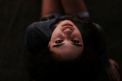 Close-up high angle view of young woman resting in darkroom