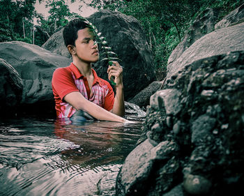 Full length of woman sitting on rock