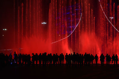 Silhouette people standing by illuminated water fountain at night