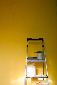 An empty ladder with paint cans on top of it ans space for text